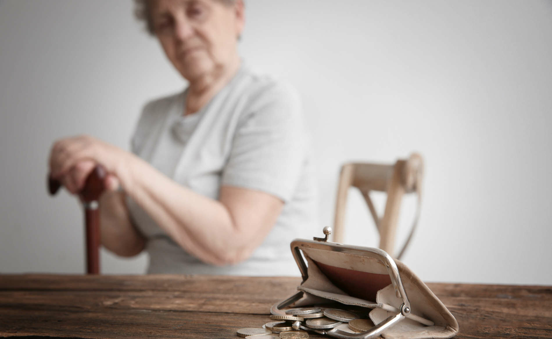 Purse with coins and blurred senior woman on background. Pov