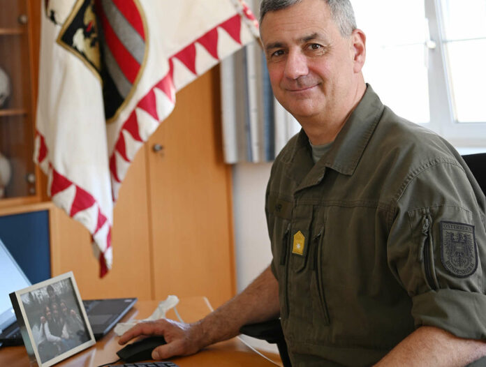 Im Büro von Kommandant Brigadier Dieter Muhr steht vor dem Computer ein Foto mit der Familie, dahinter hängt die Fahne vom Militärkommando Oberösterreich.