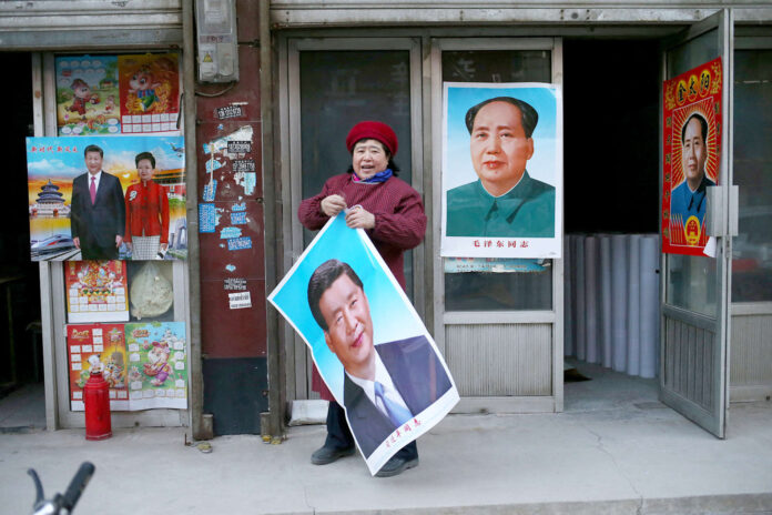 Eine Ladenbesitzerin in der chinesischen Stadt Gaobeidian: Zu Neujahr Poster des „Überragenden Führers“ Xi Jinping auf Augenhöhe mit Übervater Mao.