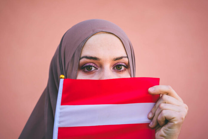 Muslim woman in a scarf holds flag of Austria