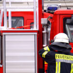 Ein Feuerwehrmann vor einem modernen Feuerwehrfahrzeug bei e