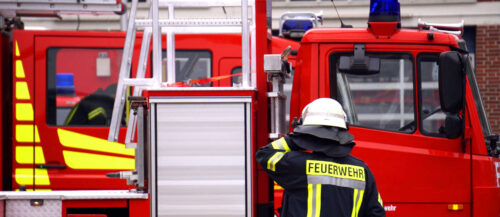 Ein Feuerwehrmann vor einem modernen Feuerwehrfahrzeug bei e