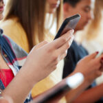 Close Up Of A Line Of High School Students Using Mobile Phon