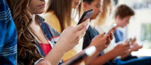 Close Up Of A Line Of High School Students Using Mobile Phon