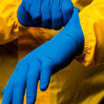 The scientist wears a yellow decontamination suit and wears