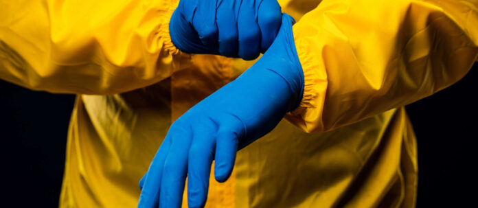 The scientist wears a yellow decontamination suit and wears