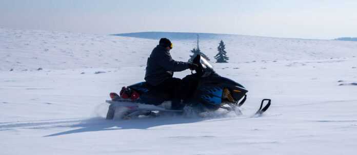 A close-up of a person on a snowmobile in a field