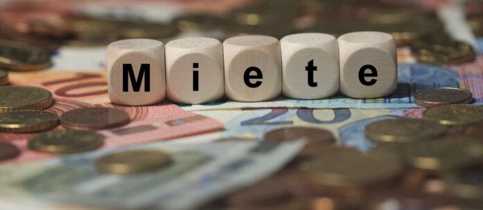 miete - Holzwrfel mit Buchstaben im Hintergrund mit Geld, G