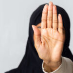 Unrecognizable muslim woman in hijab making stop gesture wit