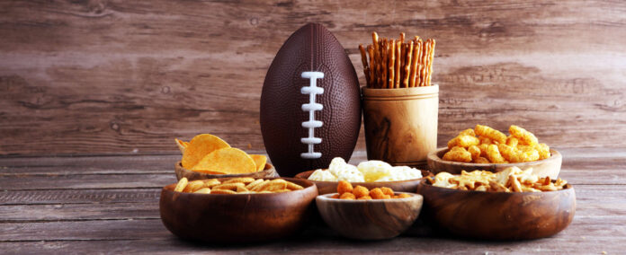 Chips, salty snacks, football on a table. Great for Bowl Gam