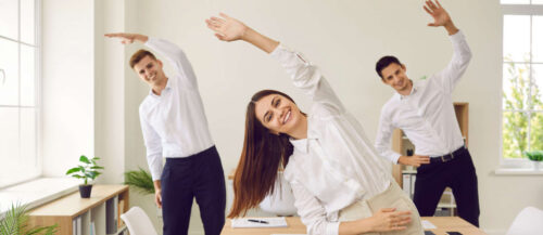 Happy smiling young business people doing stretching exercis