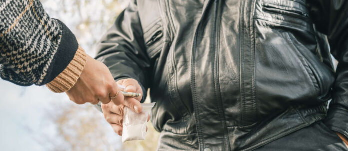 Male drug dealer sells hard drugs in a transparent plastic b