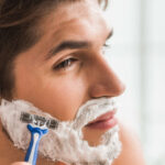 Serious guy shaving his beard