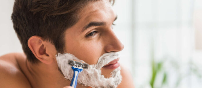 Serious guy shaving his beard