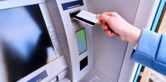 Person insert plastic credit card into street atm bank to wi