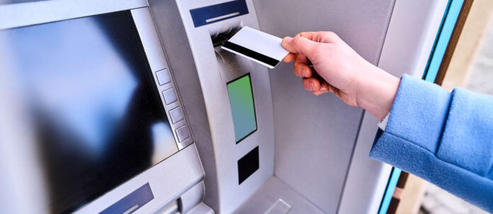 Person insert plastic credit card into street atm bank to wi