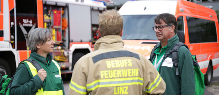 Krisenhelferin Gabriele Murauer und ihr Kollege Josef Pree besprechen mit einem Feuerwehrmann den Einsatz.