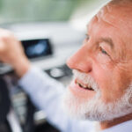 Close-up of happy senior man sitting in car in driver seat,