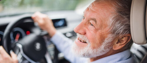 Close-up of happy senior man sitting in car in driver seat,