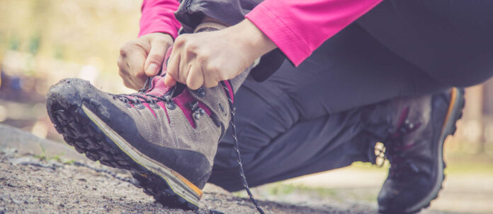 Junge Frau bindet ihre Wanderschuhe, Wanderung