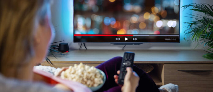 Woman relaxing at home in evening and watching TV